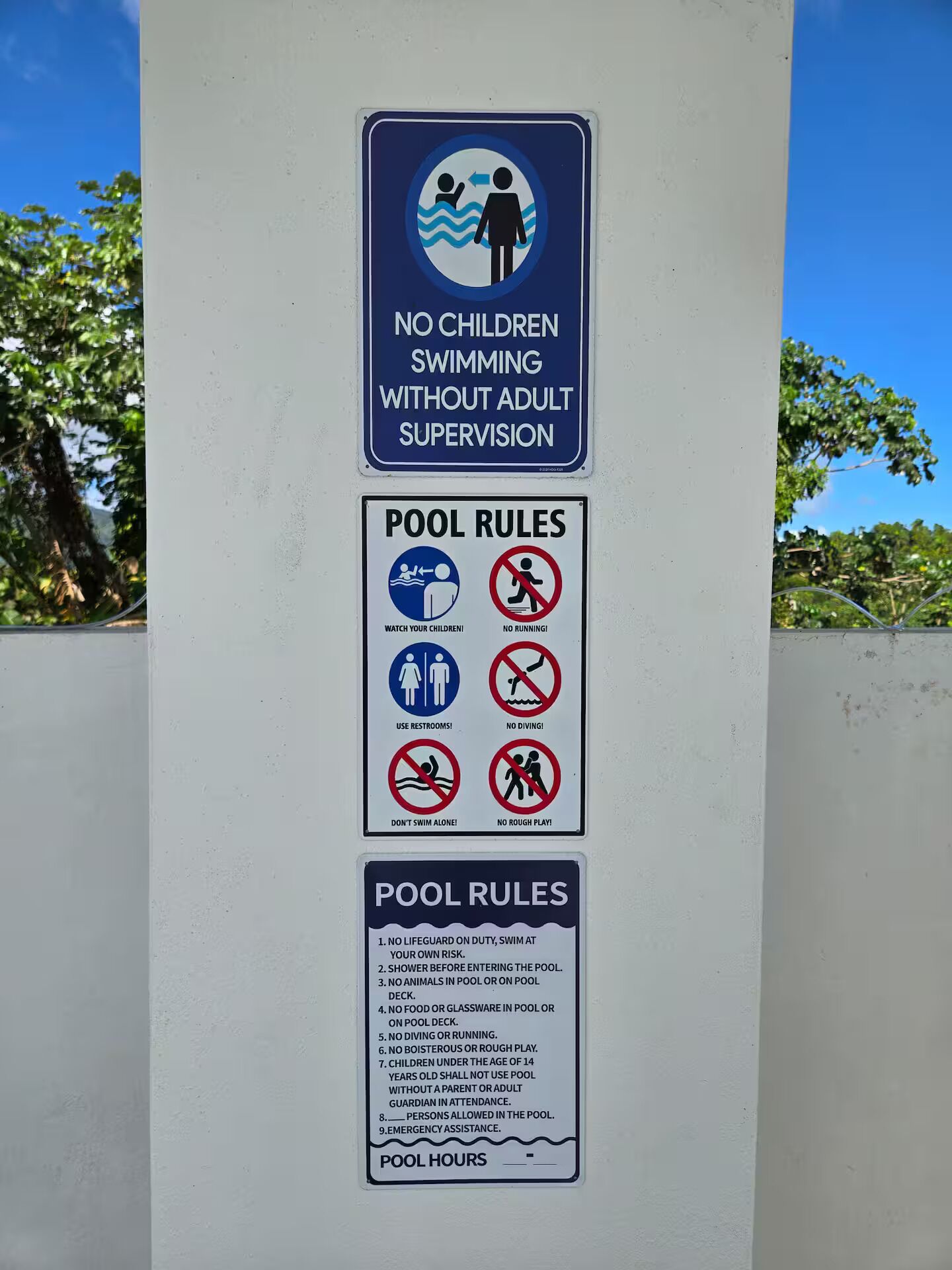 A sign with pool rules and a 'No Children Swimming Without Adult Supervision' notice.