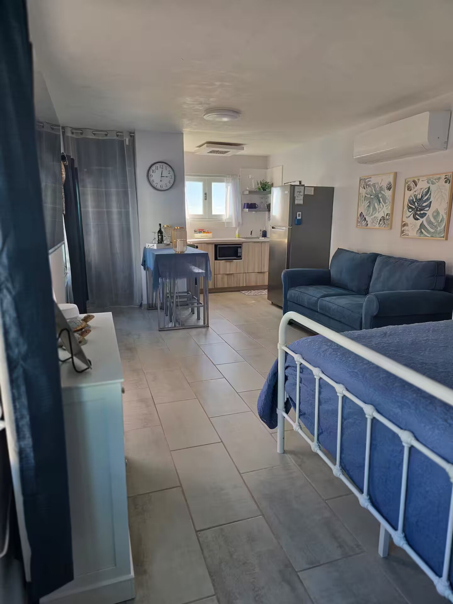 Een compacte leefruimte met een kitchenette, een eethoek en een bed.