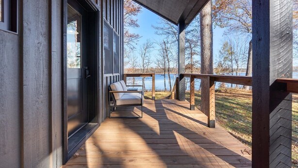 A wooden deck with a sofa and a view of a lake. - The Log Haus - Minutes from Cuyuna, Miles from Ordinary (Crosby)