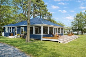 A single-story house with a covered porch, a small deck, and a grassy yard.
