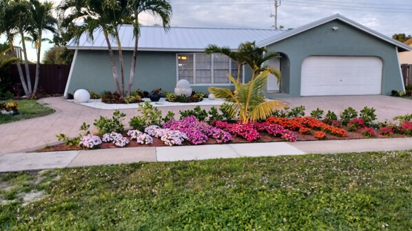 Ein Wohnhaus mit Garage, Auffahrt und einem gepflegten Garten mit verschiedenen Pflanzen und Blumen.