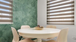 Une table ronde avec quatre chaises, un bol de collations et un mur vert à texture.