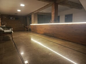 Un espace d’accueil avec un comptoir en bois, un banc et un sol carrelé.