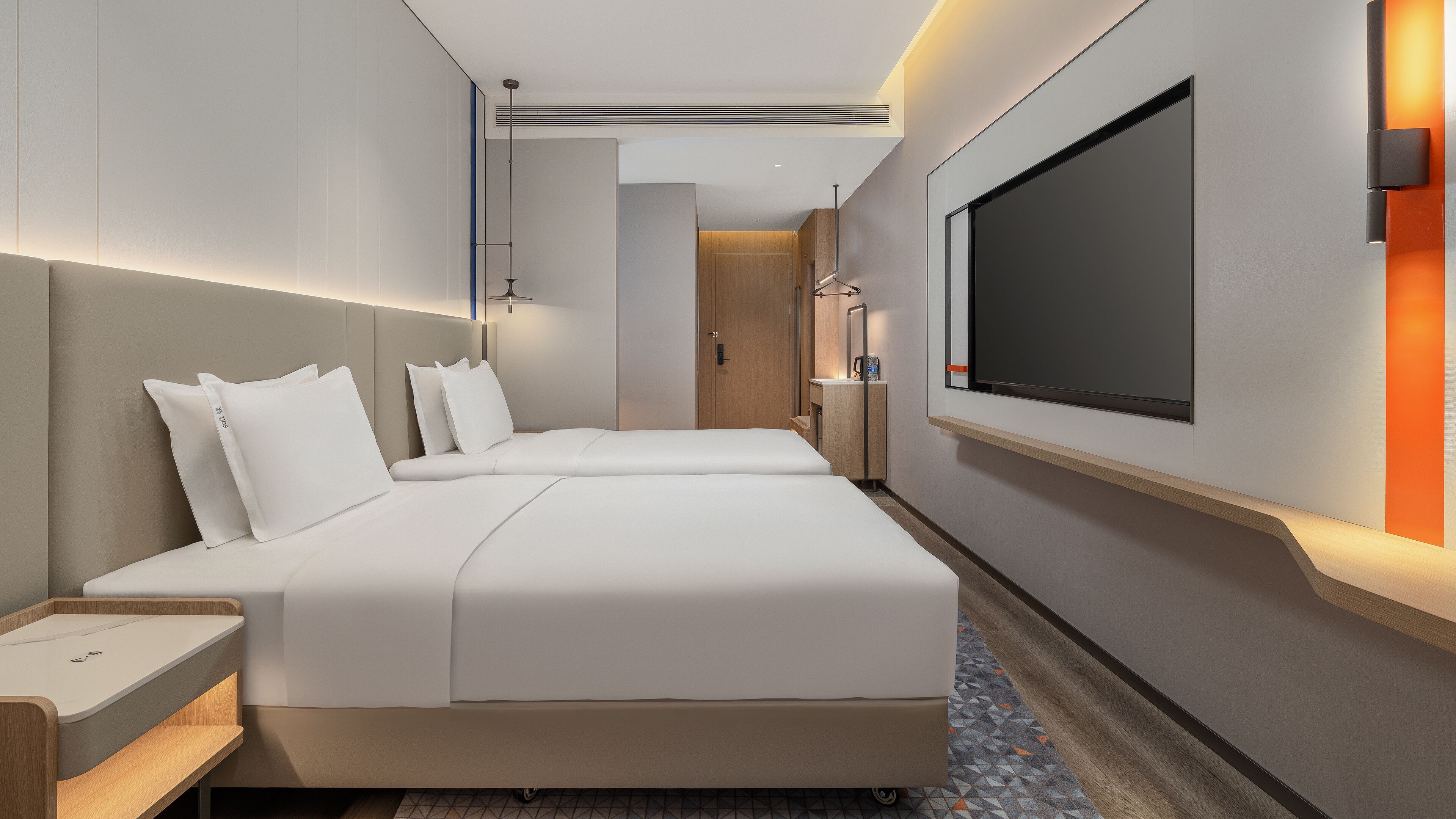 A hotel room with two beds, a TV, a bedside table, and a bathroom visible through an open door.