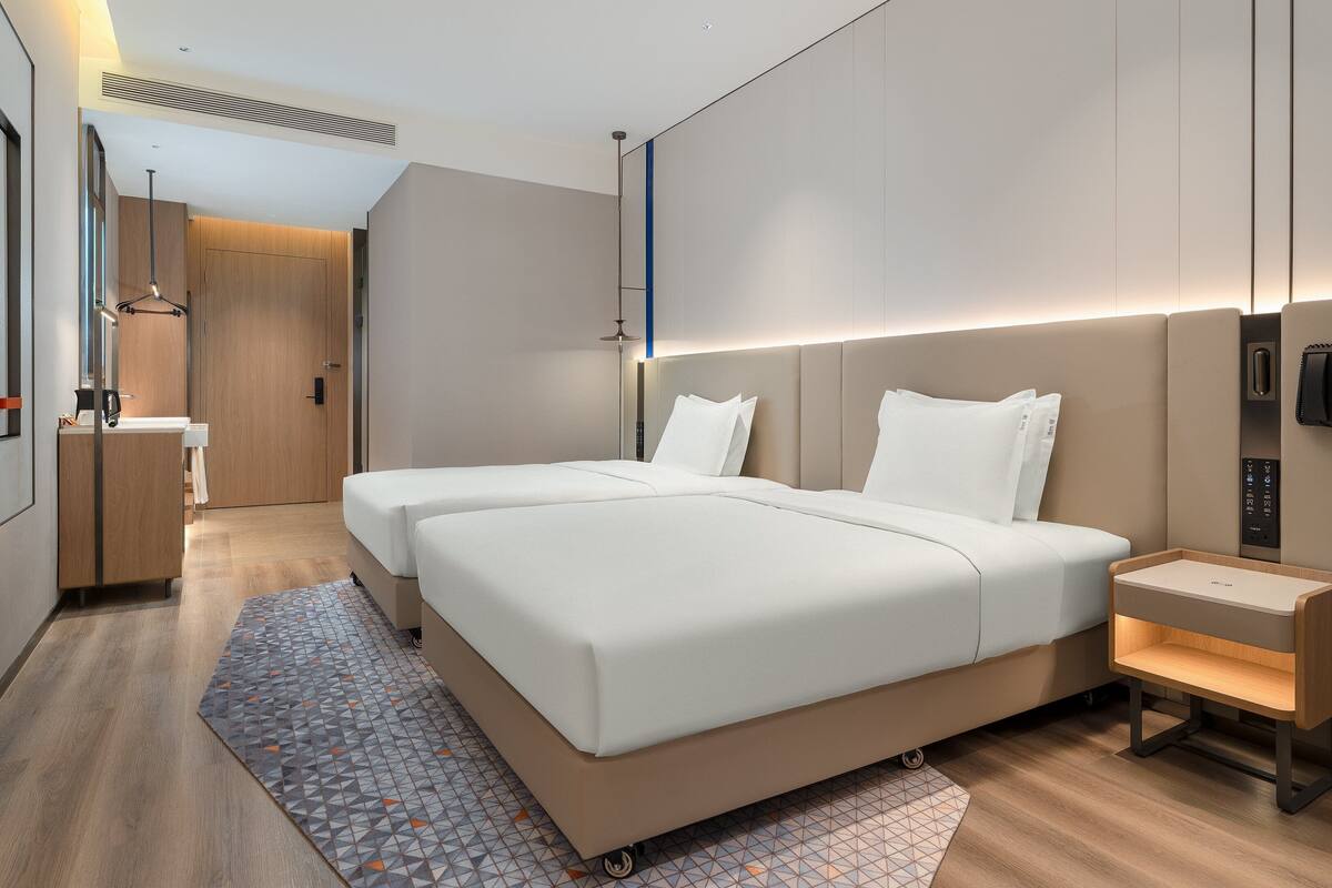 A modern hotel room with a large bed, bedside tables, a desk, and a bathroom.