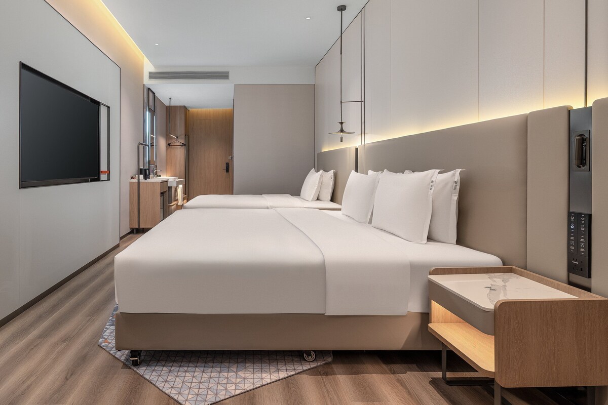 Une chambre d’hôtel moderne, dotée d’un grand lit, de tables de chevet, d’une télévision et d’un bureau.