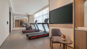 A hotel room with a treadmill, a small table with a vase, and a large mirror. - Holiday Inn Express Kunming Dianchi Rixin Road By Ihg (Kunming)