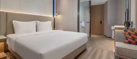 Una habitación de hotel moderna con una cama grande, un escritorio pequeño y una zona de estar.