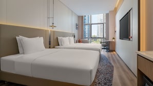 A hotel room with two beds, a desk, a chair, a TV, and a large window with a city view. - Holiday Inn Express Kunming Dianchi Rixin Road By Ihg (Kunming)