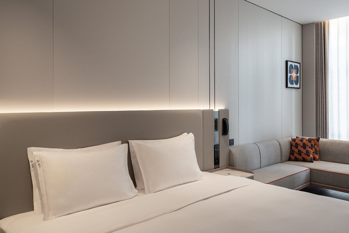 Une chambre d’hôtel moderne avec un grand lit, un canapé et une petite table.