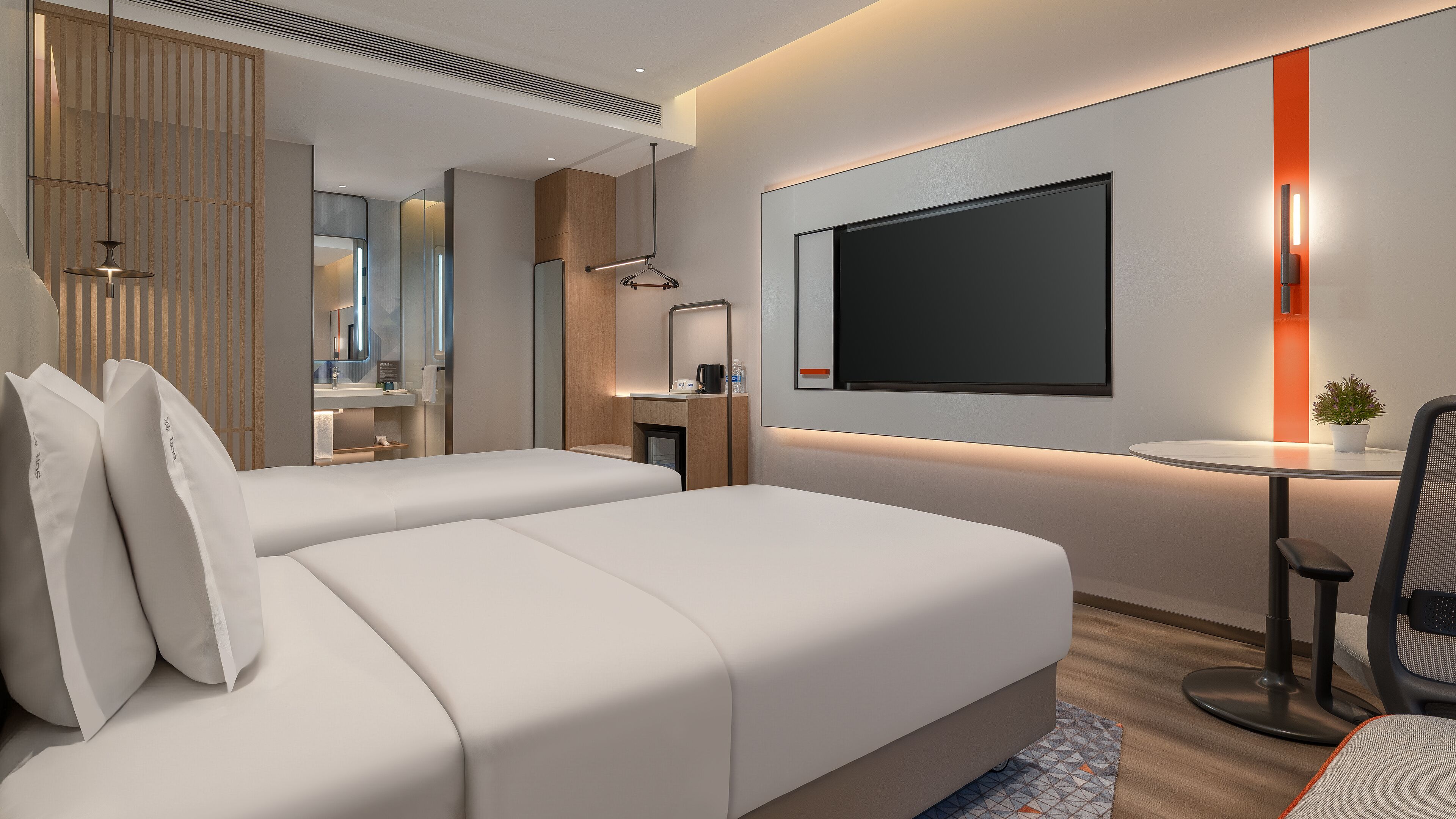 A modern hotel room with two beds, a desk, a TV, and a small plant.