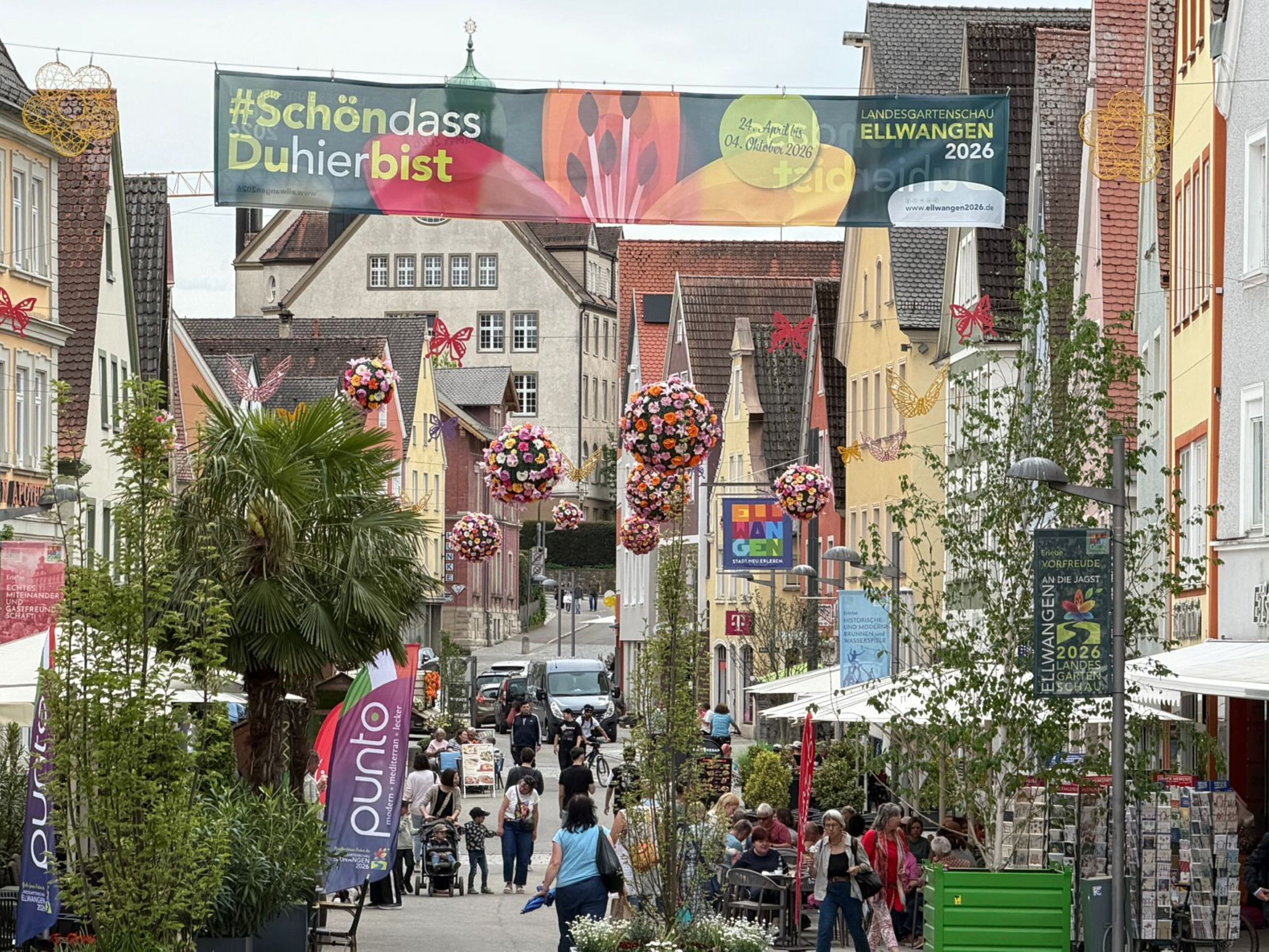 A street with a banner for an event, buildings, and outdoor seating areas.