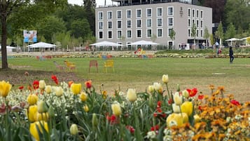 Un edificio de estilo arquitectónico moderno, un campo cubierto de césped con flores coloridas y zonas de estar al aire libre.
