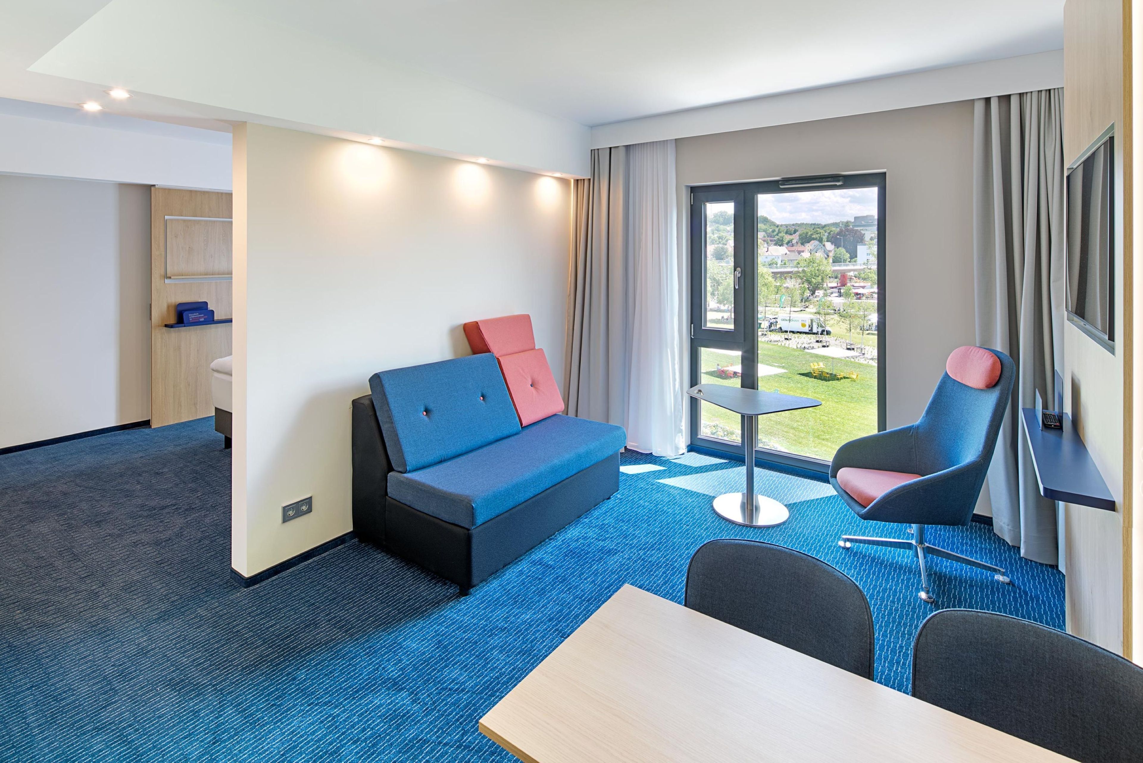 A hotel room with a sofa, armchair, and a small table.