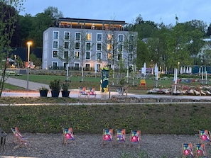 A modern building with multiple windows, outdoor seating, and a landscaped area with chairs and plants. - Holiday Inn Express & Suites Ellwangen by IHG (Ellwangen)