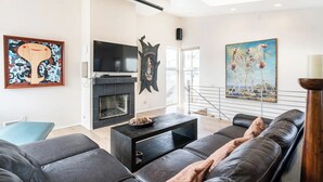 Una sala de estar moderna con chimenea, televisor de pantalla plana y obras de arte en las paredes.