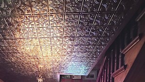 Un escalier avec une rampe en bois et un plafond orné de motifs.