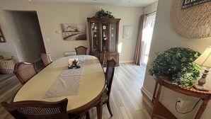 A dining area with a round table, chairs, a cabinet, and a potted plant.