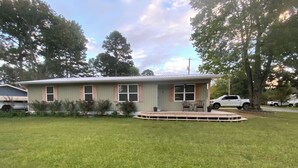 A single-story house with a front porch, a small deck, and a lawn.