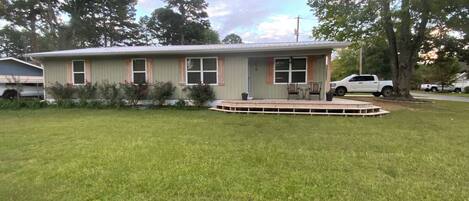 A single-story house with a front porch, a small deck, and a lawn.