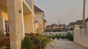 A residential area with paved walkways, stone pillars, and potted plants. - Dazzle Hotel and Apartment (Abuja)