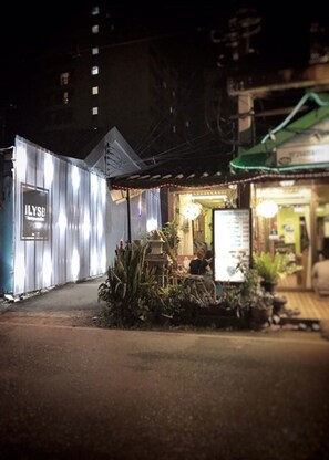 A street view at night with a restaurant named 'ILYSB' in the foreground. - Ilysb I Love You So Bed Hostel (Chiang Mai)