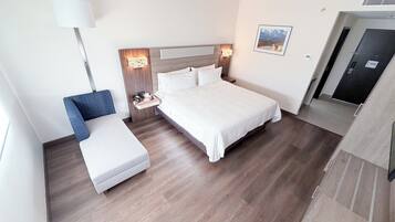 Een hotelkamer met een bed, nachtkastje, stoel, lamp en een schilderij aan de muur.