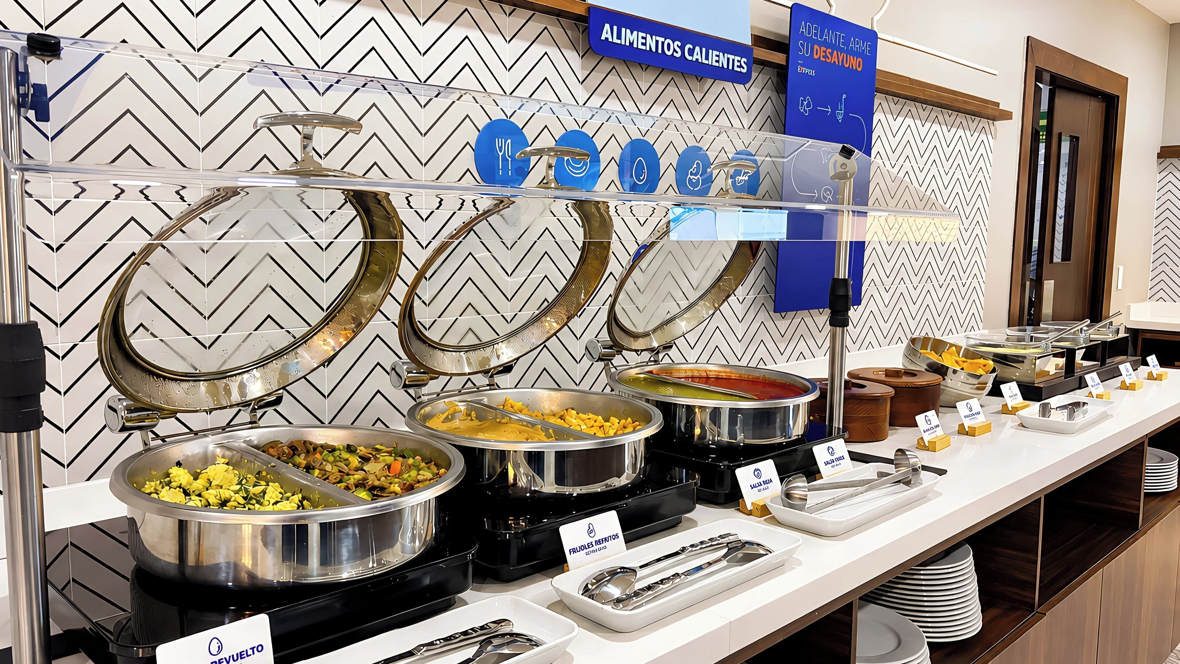 A buffet setup with various food stations, including a pasta station and a fruit station, with clear signage for each.