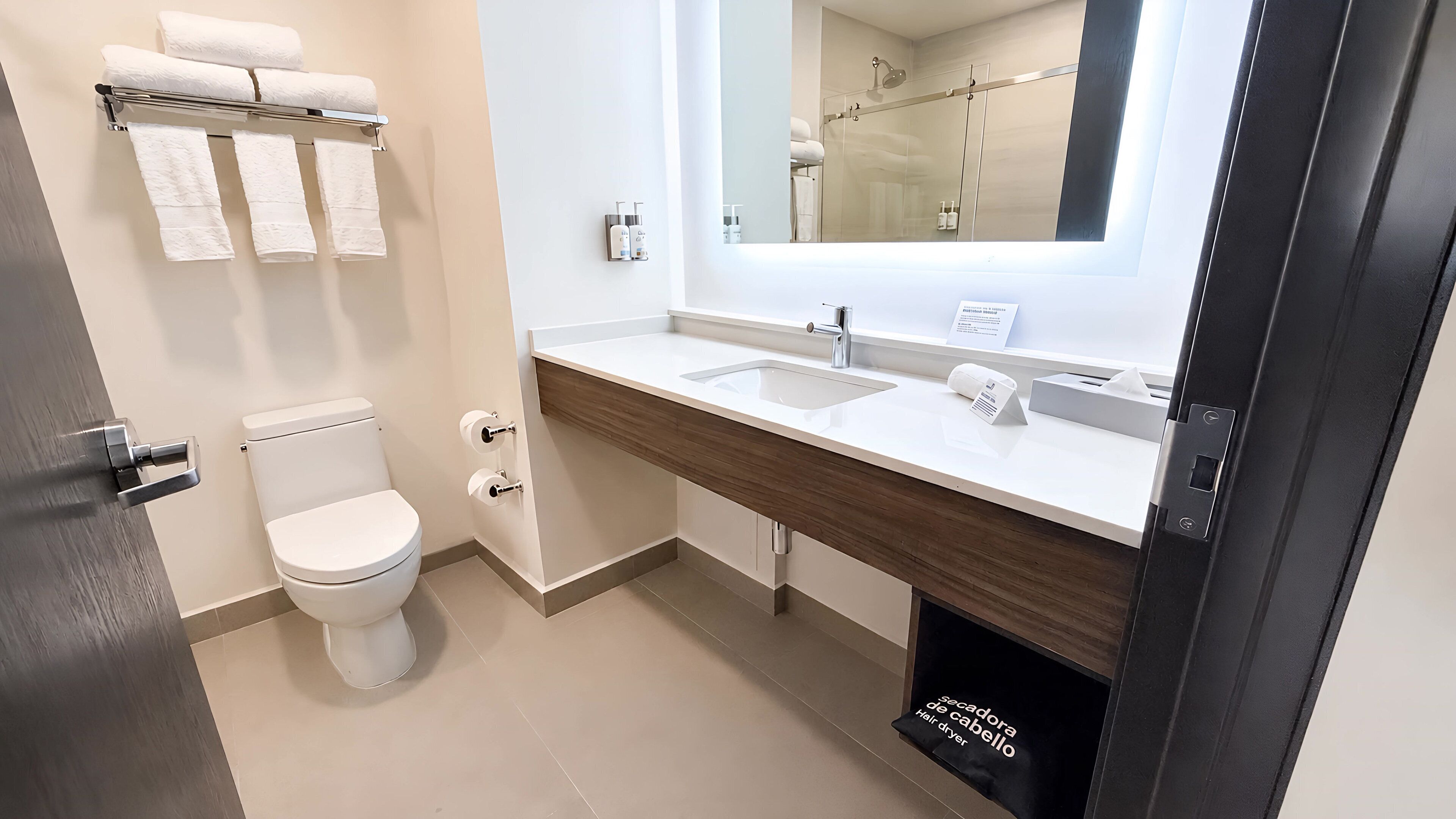 Un baño moderno con inodoro, lavabo y espejo.