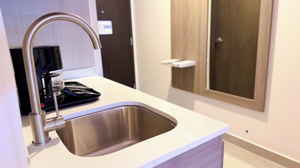 Une cuisine moderne dotée d’un évier en acier inoxydable, d’une machine à café et d’un meuble en bois.