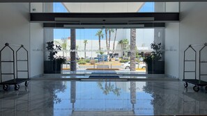 Un hall d’entrée spacieux doté d’un sol réfléchissant, de grandes fenêtres et offrant une vue sur le parking extérieur.