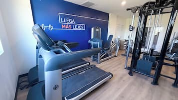 Et fitnessrum med løbebånd, vægtbænk og squat rack.
