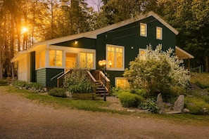 A two-story house with a front porch, a staircase, and a garden. - Peaceful, Curated Lakes Region Hideaway (Meredith)