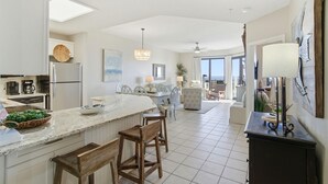 Une cuisine moderne dotée d’un grand îlot central, de tabourets de bar et d’un coin repas offrant une vue agréable.