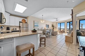 A spacious kitchen with a large island, modern appliances, and a dining area with a view. - Phoenix 10 114 (Orange Beach)