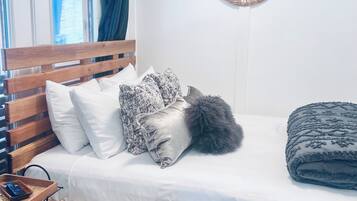 A bedroom with a wooden bed, white bedding, and a woven wall hanging.