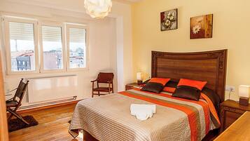 Habitación de hotel con una cama grande, cabecera de madera, una silla, ventana con persianas y una obra de arte en la pared.