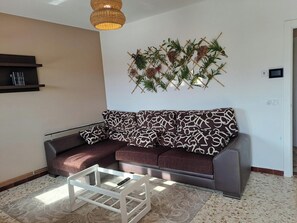 A living room with a sofa, a coffee table, a wall-mounted plant, and a hanging light fixture. - Torre Plaza 5. A spacious apartment in Boiro, beaches and terraces. (BOIRO)