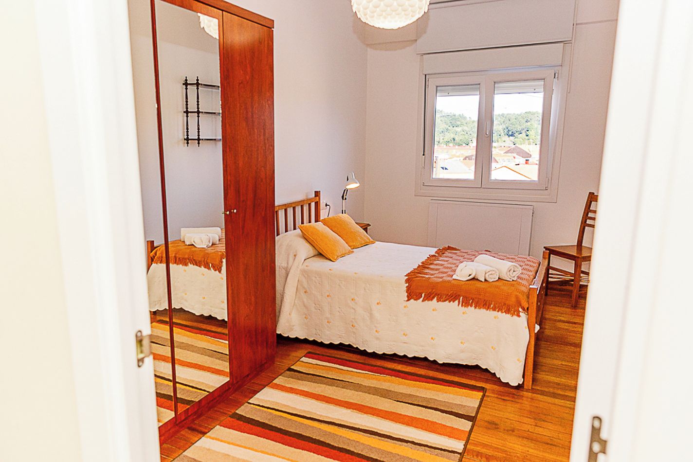 Een slaapkamer met een bed, een stoel, een raam en een deur.