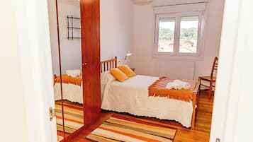 Een slaapkamer met een bed, een stoel, een raam en een deur.
