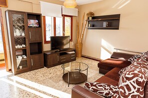 Un salon comprenant un canapé, un téléviseur, un meuble et une petite table.