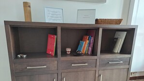 A wooden cabinet with three drawers and two shelves, containing books and a small decorative item. - Torre Plaza 5. A spacious apartment in Boiro, beaches and terraces. (BOIRO)