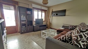 A living room with a sofa, a coffee table, a TV, and a bookshelf. - Torre Plaza 5. A spacious apartment in Boiro, beaches and terraces. (BOIRO)