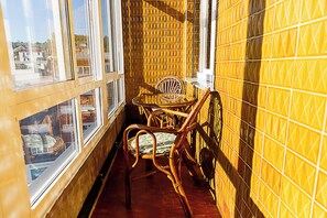 A narrow balcony with wicker furniture, large windows, and yellow patterned walls.