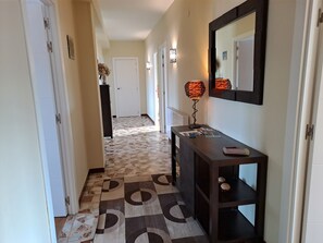 A hallway with patterned flooring, a console table with a lamp, and a mirror on the wall. - Torre Plaza 5. A spacious apartment in Boiro, beaches and terraces. (BOIRO)
