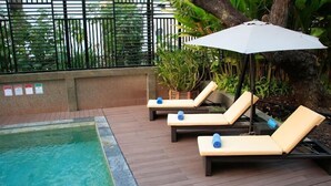 Un espace aménagé au bord de la piscine, avec des chaises longues et un parasol.