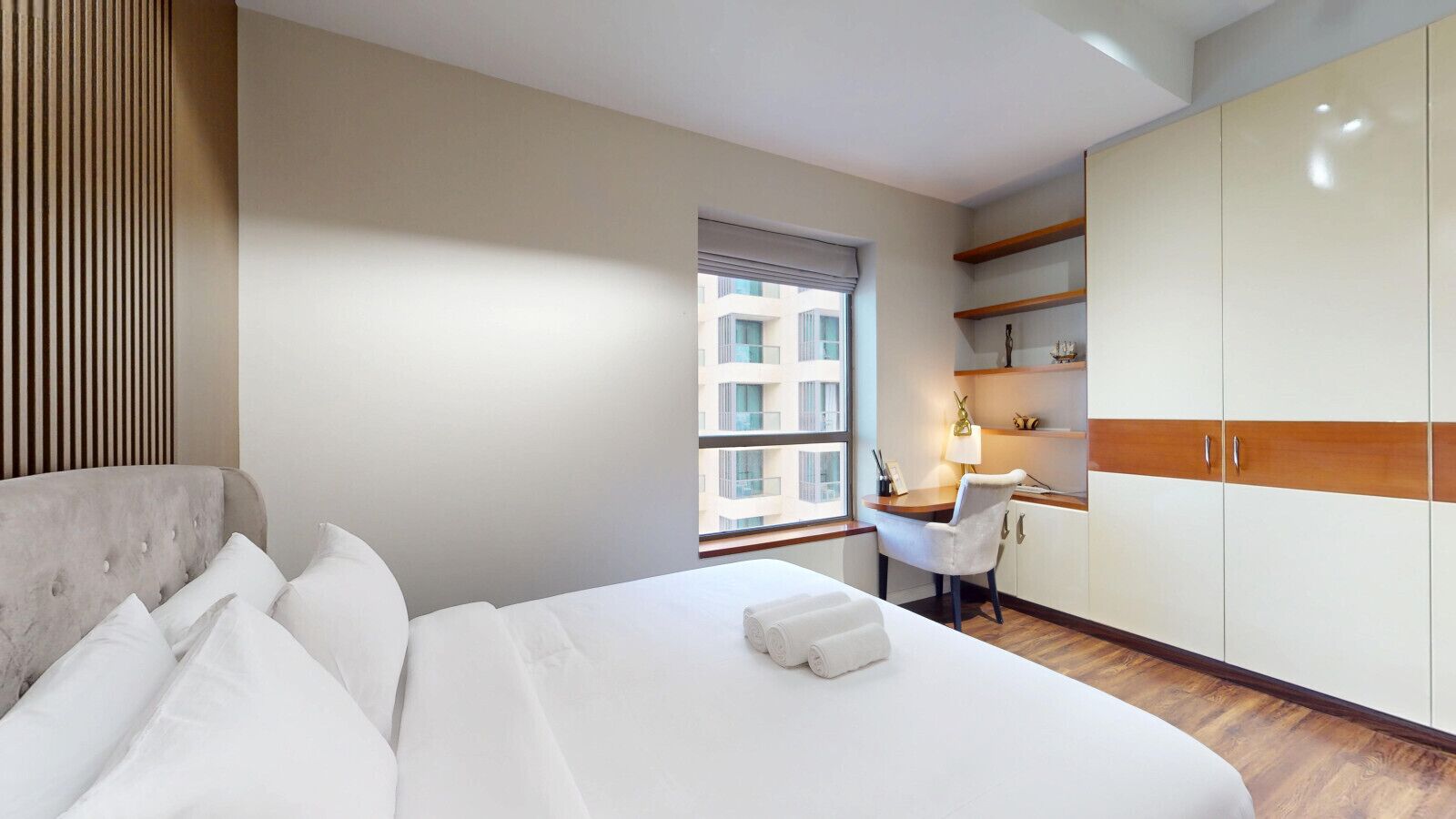 A hotel room with a bed, a desk, and a wardrobe.