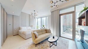 A modern hotel room with a large bed, a sofa, a small table, and a large window offering a city view. - Chic Upgraded Studio l City Views l Dubai Marina (Dubai Marina)