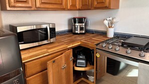 Una cucina con mobili in legno, un forno a microonde, una macchina da caffè e un piano cottura.