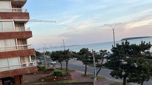 A residential building with a balcony, a view of the sea, and a parking area with cars and trees. - Oceanfront Beach House at Parada 23 La Mansa - Direct Beach Access (Punta del Este)